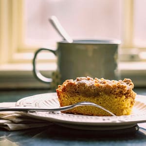 sourdough discard coffee cake - cake on a plate with a fork and green coffee cup