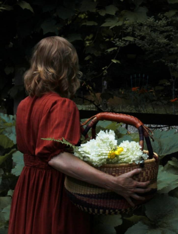 Me in the vegetable garden holding a basket of hydrangeas. I am wearing a red linen dress